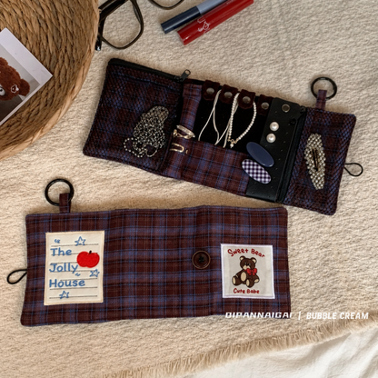 Open organizer with necklace tabs, ring holder, and zip pockets